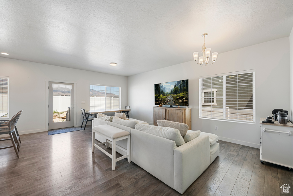 Living area with a chandelier, dark wood-style flooring, recessed lighting, and a textured ceiling