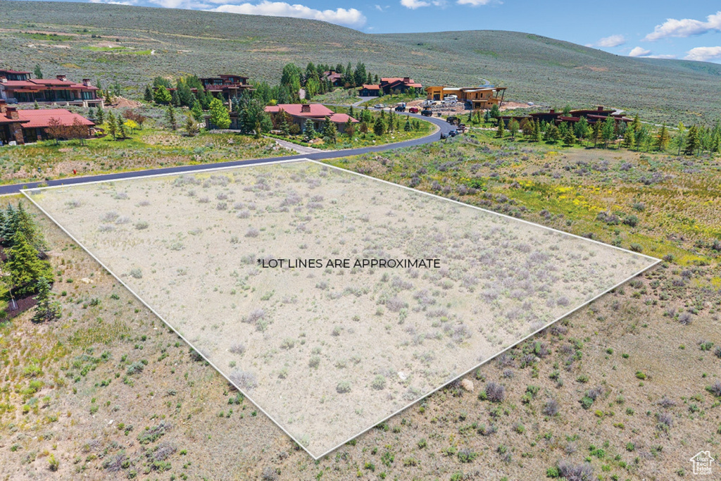Aerial view of property and surrounding area featuring a mountainous background and property boundaries highlighted