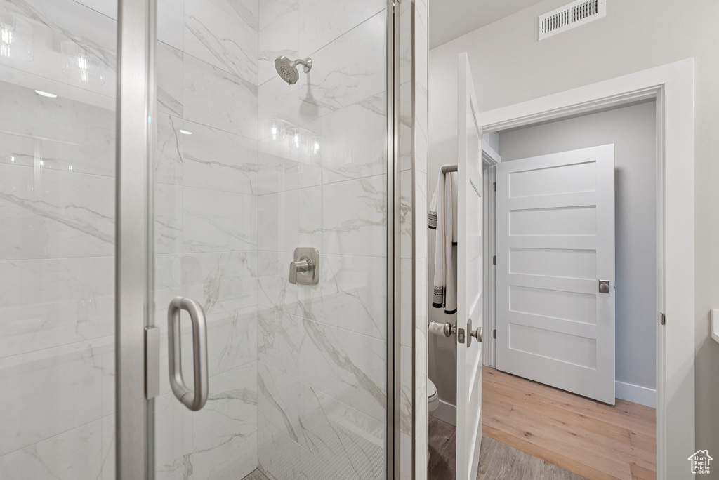 Full bathroom with wood finished floors and a marble finish shower