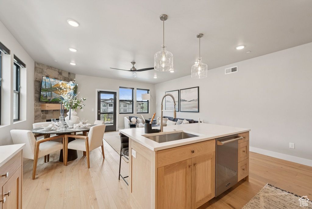 Kitchen with light brown cabinetry, dishwasher, open floor plan, light wood-style flooring, and recessed lighting