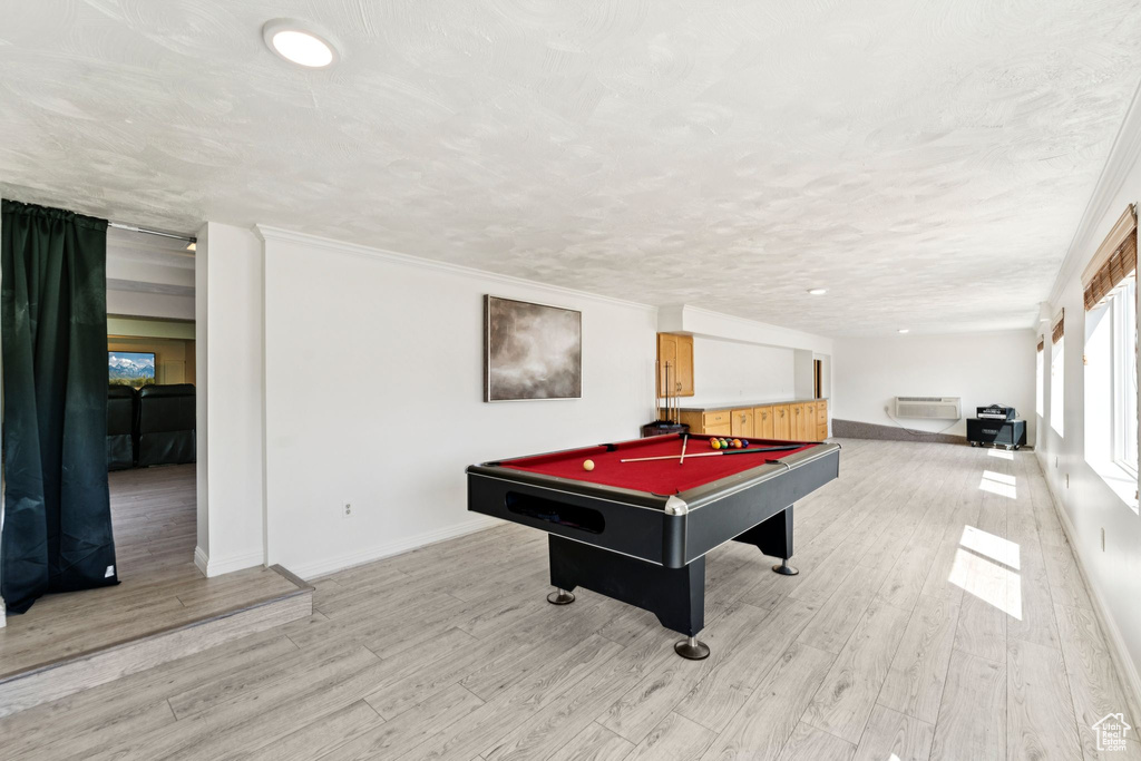 Recreation room with pool table, light wood finished floors, a wall mounted air conditioner, and a textured ceiling