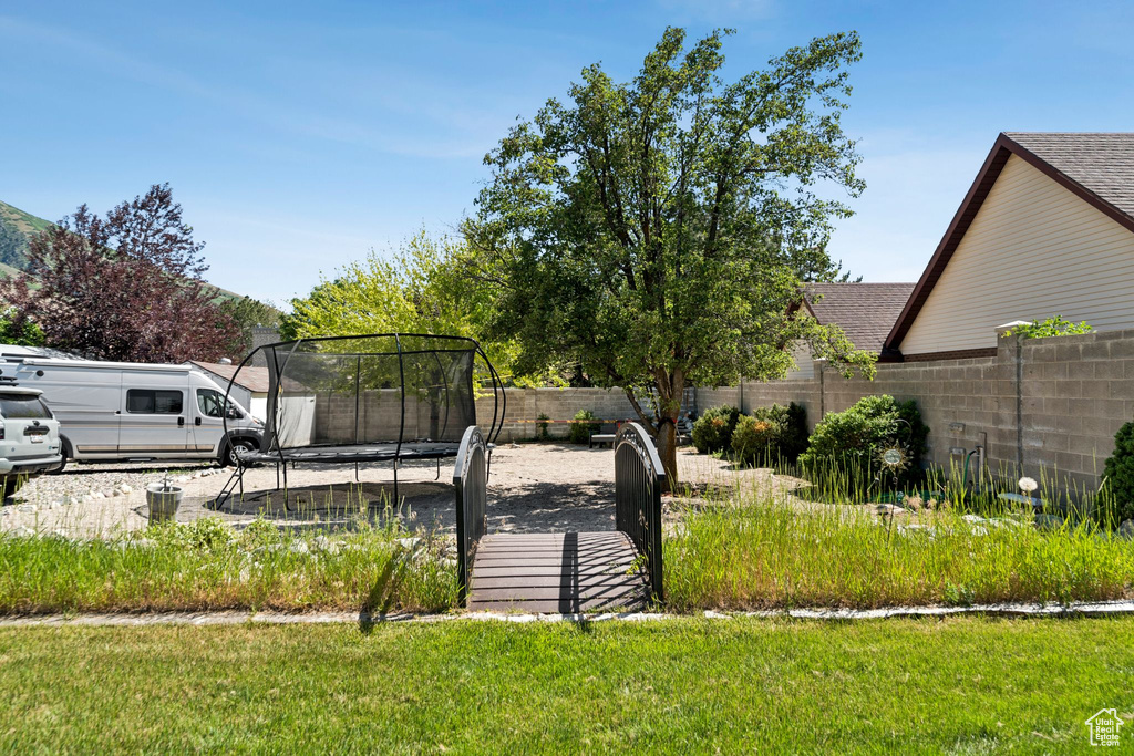 Fenced backyard featuring a trampoline