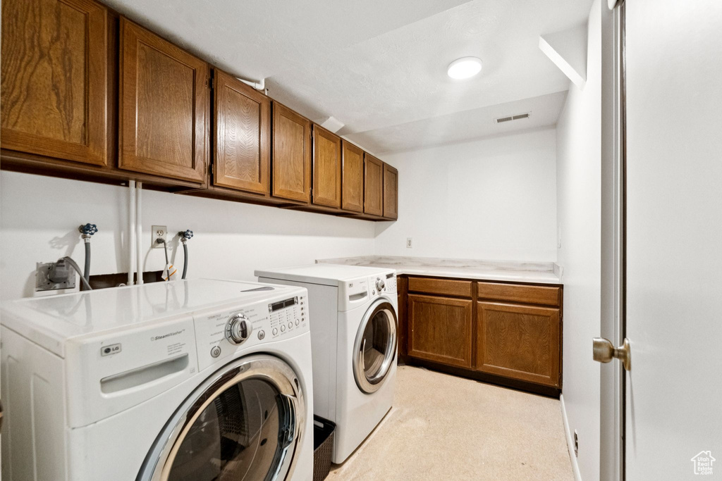 Laundry room with independent washer and dryer, cabinet space, and light colored carpet