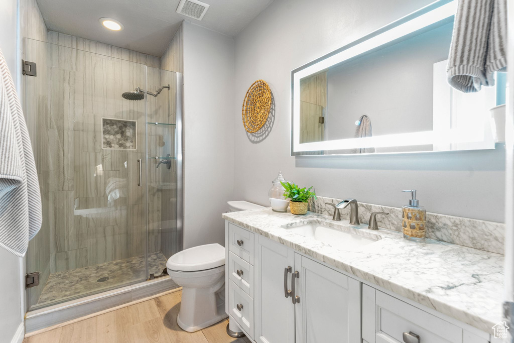 Bathroom with vanity, a shower stall, wood finished floors, and recessed lighting