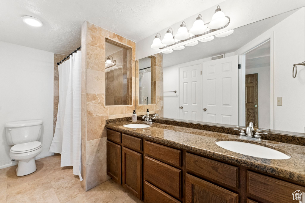 Full bathroom with double vanity, a shower with shower curtain, and tile patterned flooring
