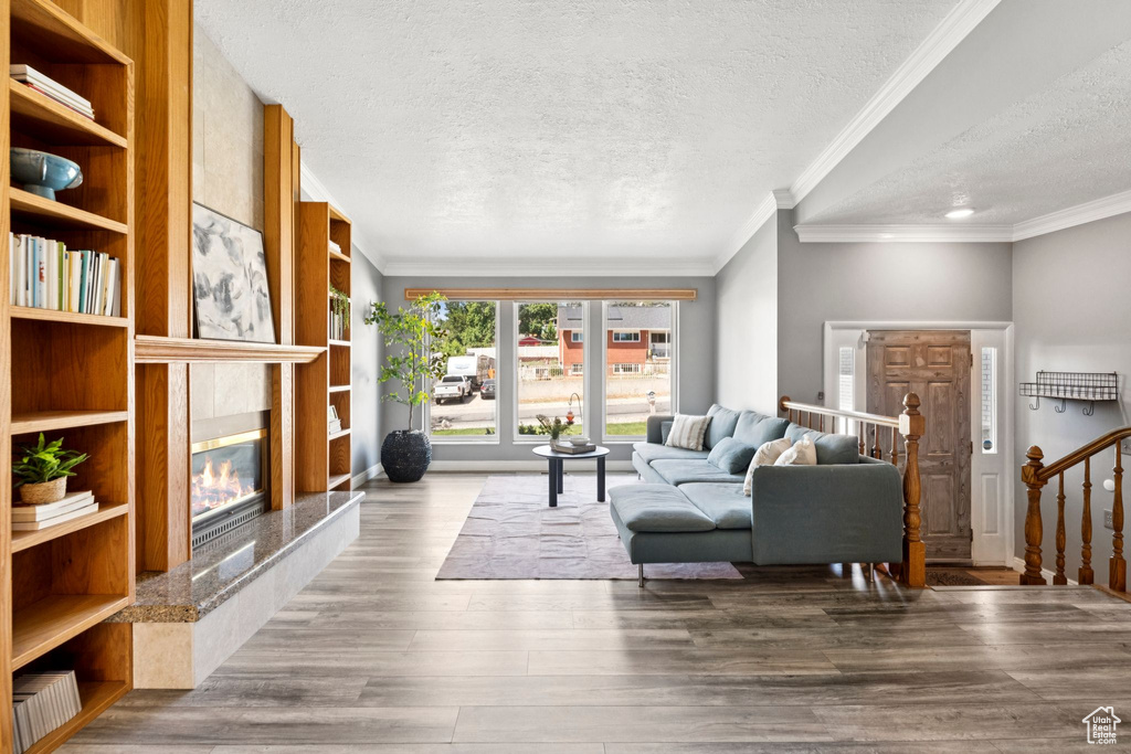 Living area with a textured ceiling, a premium fireplace, wood finished floors, and ornamental molding