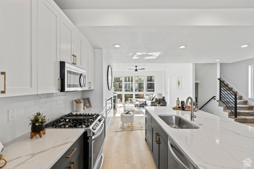 Kitchen with appliances with stainless steel finishes, white cabinets, open floor plan, a ceiling fan, and recessed lighting