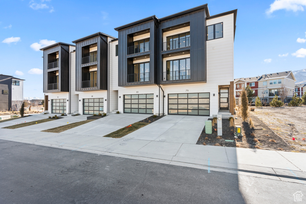 Contemporary home with an attached garage, driveway, a residential view, and board and batten siding