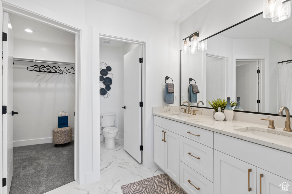 Bathroom with double vanity, marble look tiles, and a spacious closet