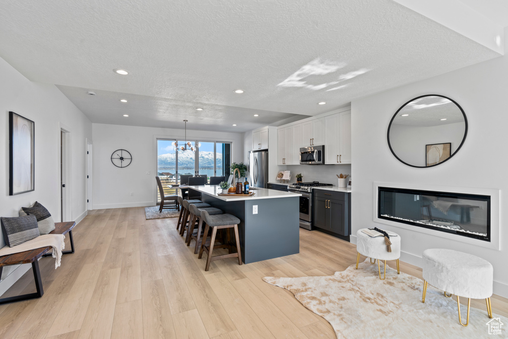 Kitchen featuring appliances with stainless steel finishes, a center island, a breakfast bar area, a textured ceiling, and light wood finished floors