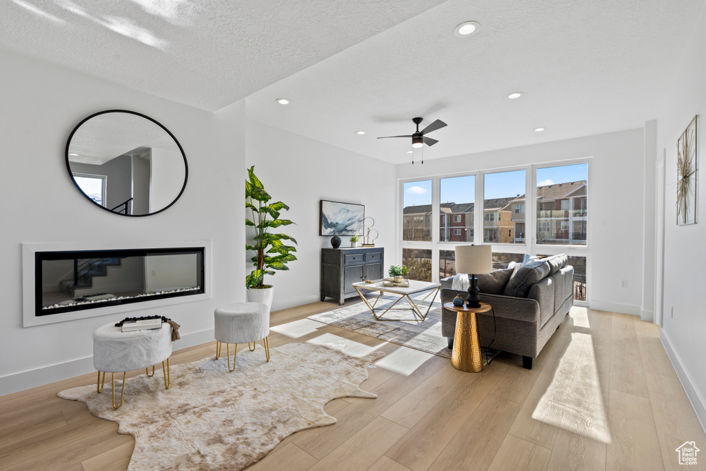 Living area featuring wood finished floors, ceiling fan, a textured ceiling, and recessed lighting