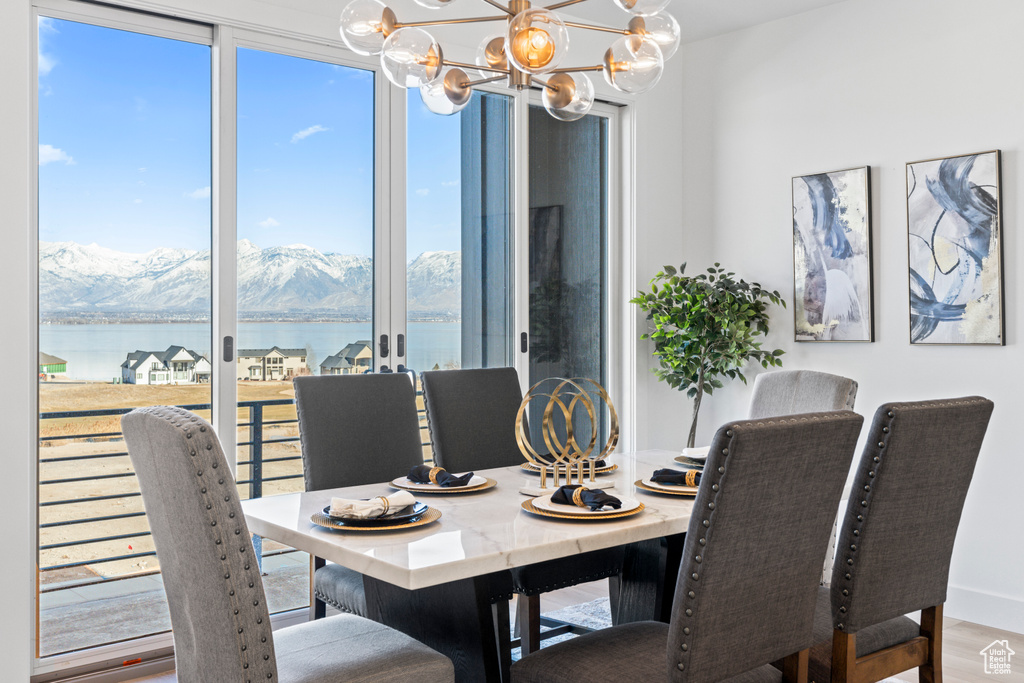 Dining room with a water and mountain view, a chandelier, and wood finished floors