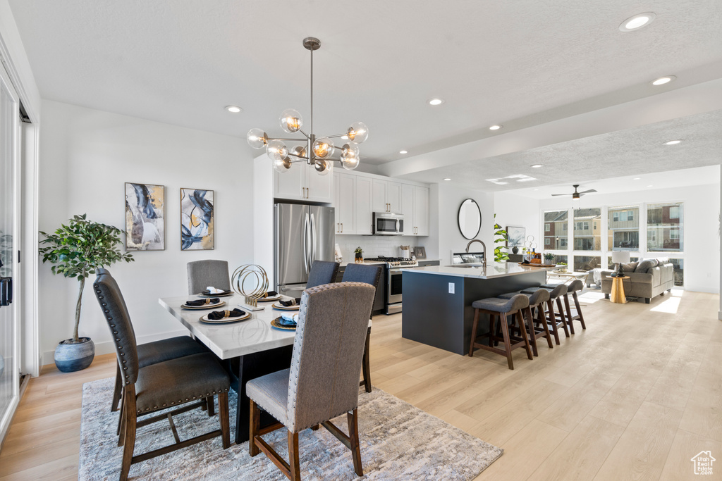Dining space with light wood-style flooring, recessed lighting, ceiling fan, and a chandelier