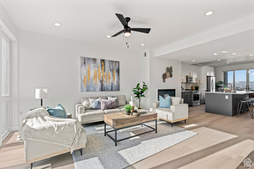 Living room with light wood-style flooring, recessed lighting, and ceiling fan