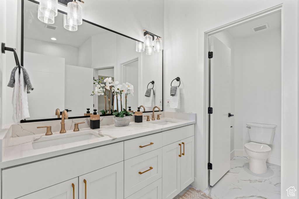 Bathroom with double vanity and marble finish flooring