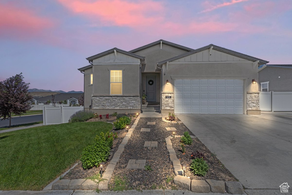 Ranch-style house featuring stone siding, an attached garage, driveway, and board and batten siding