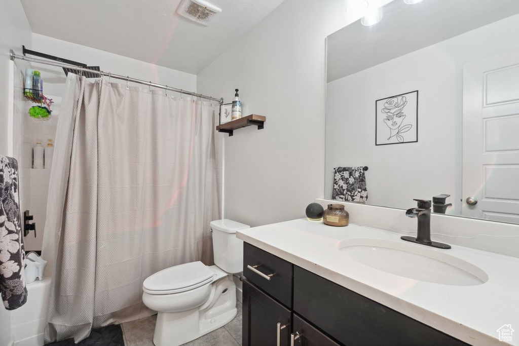 Bathroom featuring vanity, shower / tub combo with curtain, and tile patterned flooring