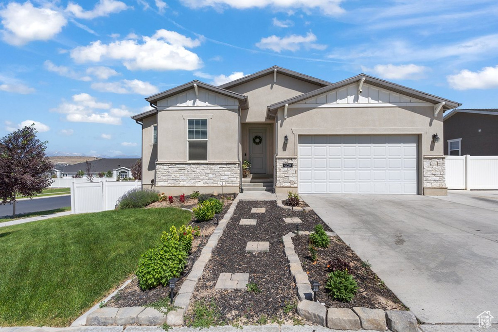 Ranch-style house featuring stone siding, an attached garage, concrete driveway, stucco siding, and board and batten siding