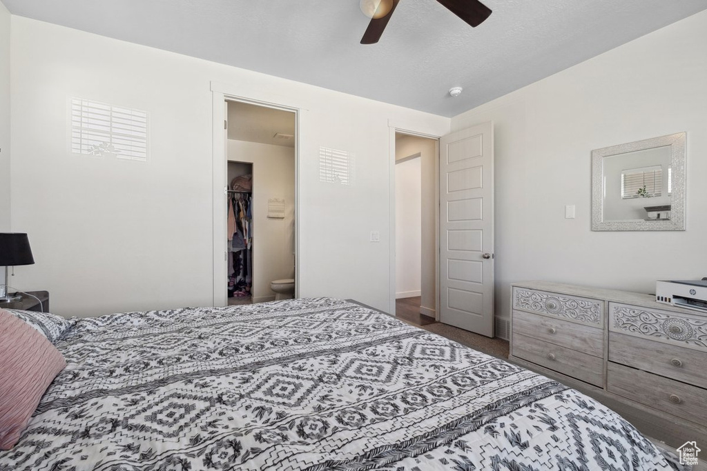Carpeted bedroom with a spacious closet and ceiling fan