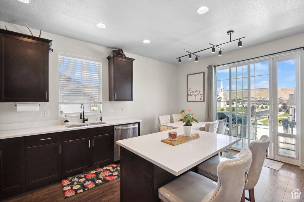 Kitchen featuring dishwasher, a breakfast bar area, plenty of natural light, light countertops, and recessed lighting