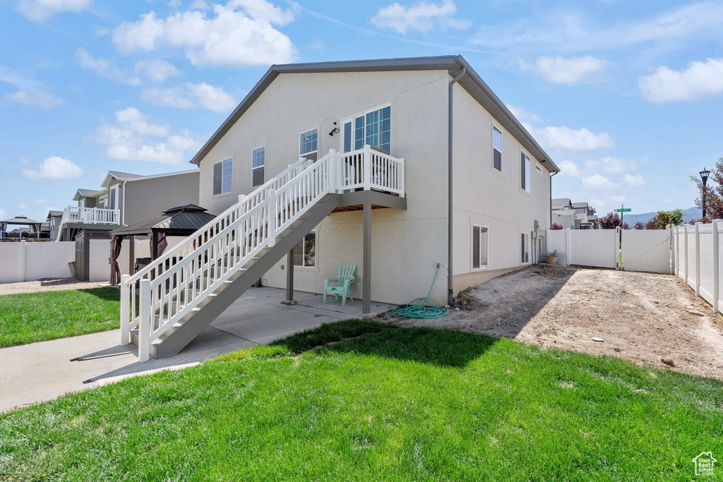 Back of property with a fenced backyard, a gate, a patio, stucco siding, and a gazebo