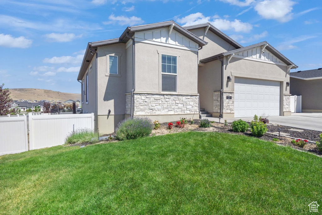 View of front of home with stone siding, a garage, driveway, board and batten siding, and stucco siding