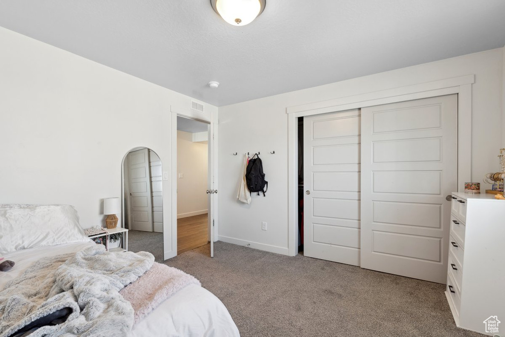 Carpeted bedroom with a closet and baseboards