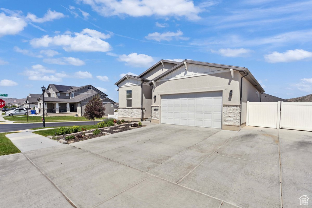 View of front of home with stone siding, an attached garage, concrete driveway, and stucco siding