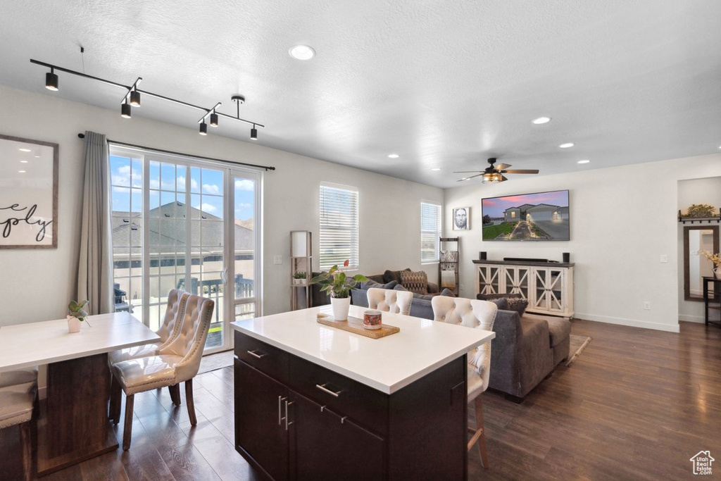 Kitchen featuring ceiling fan, dark wood-style floors, a kitchen breakfast bar, light countertops, and recessed lighting