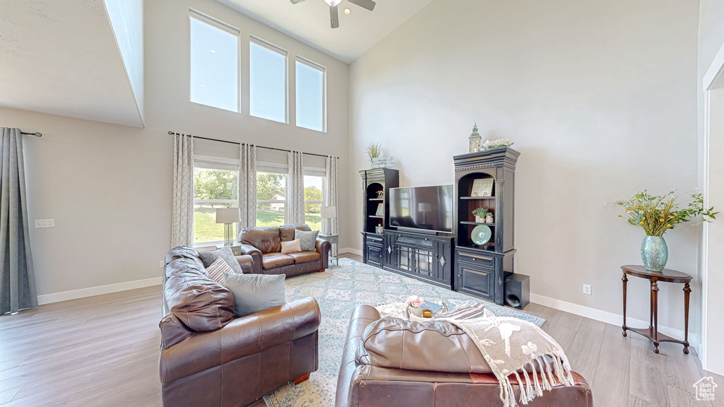Living area with high vaulted ceiling, light wood-type flooring, and ceiling fan