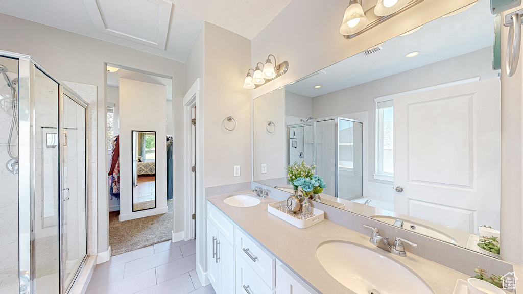 Ensuite bathroom featuring healthy amount of natural light, tile patterned floors, a stall shower, and double vanity