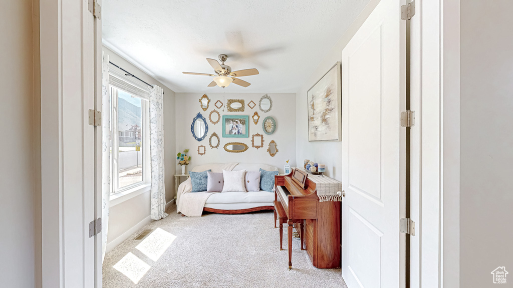 Living area with light colored carpet and a ceiling fan