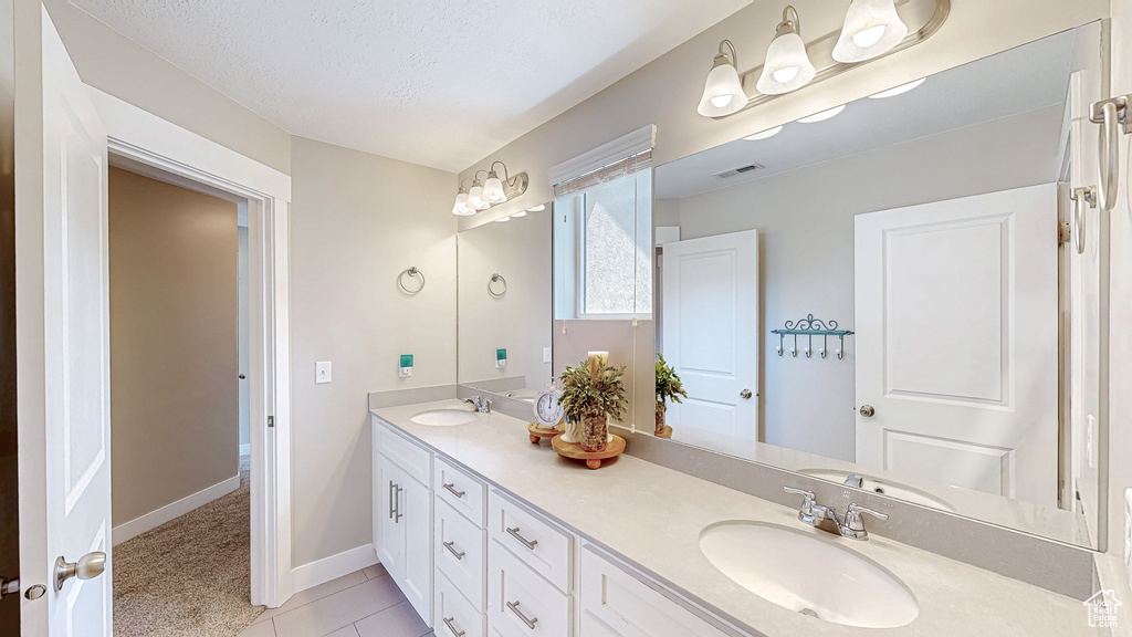 Bathroom featuring double vanity, tile patterned flooring, and a textured ceiling