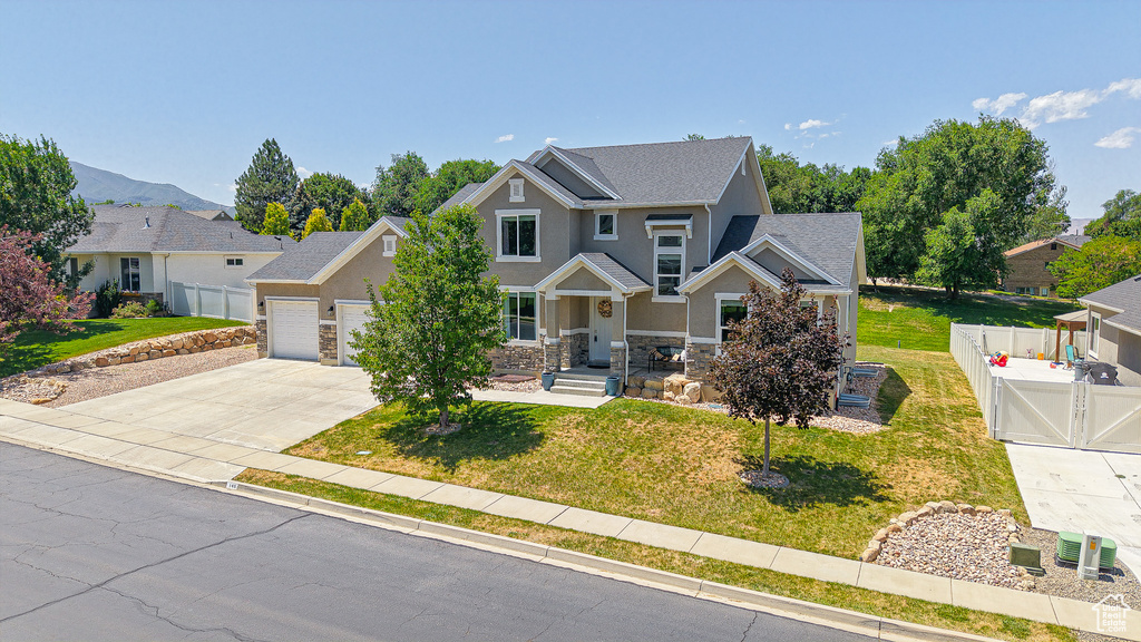 View of front facade with stone siding, an attached garage, concrete driveway, stucco siding, and a gate