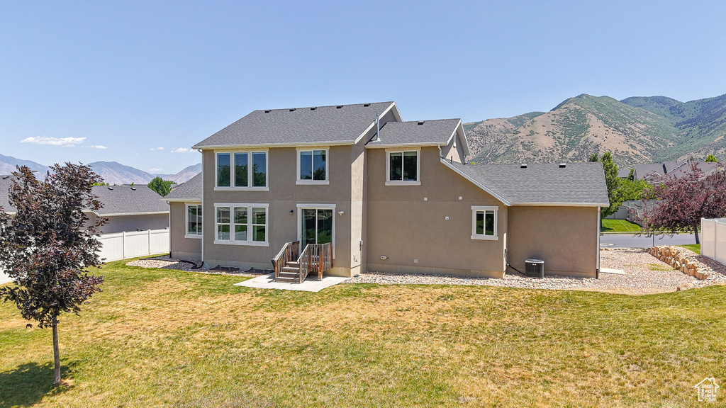 Back of property featuring stucco siding, a mountain view, and roof with shingles