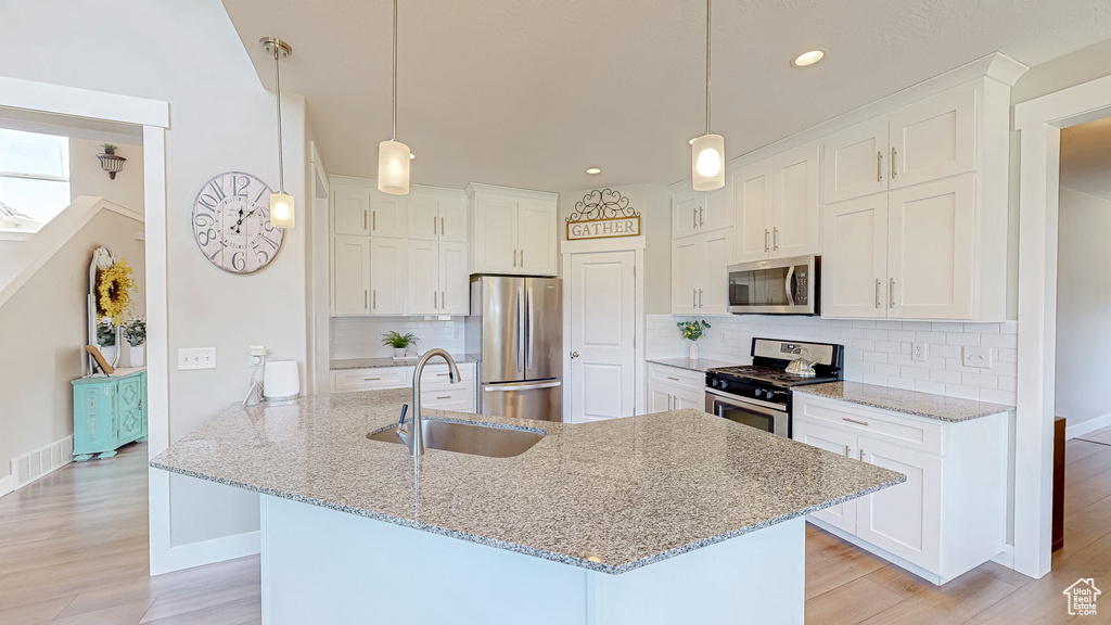 Kitchen featuring appliances with stainless steel finishes, light wood-style flooring, white cabinetry, tasteful backsplash, and recessed lighting