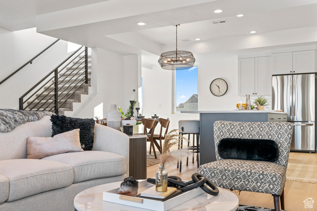 Living area with stairs, light wood finished floors, recessed lighting, a tray ceiling, and a chandelier