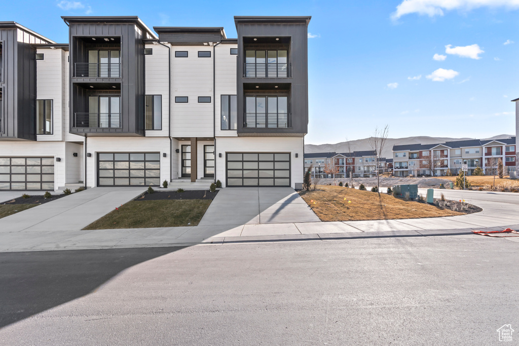 View of front facade with a residential view, a garage, driveway, and board and batten siding