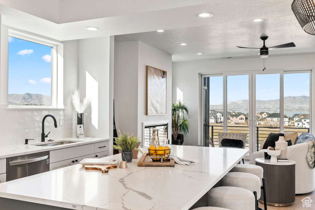 Kitchen with a mountain view, dishwasher, light stone countertops, decorative backsplash, and recessed lighting