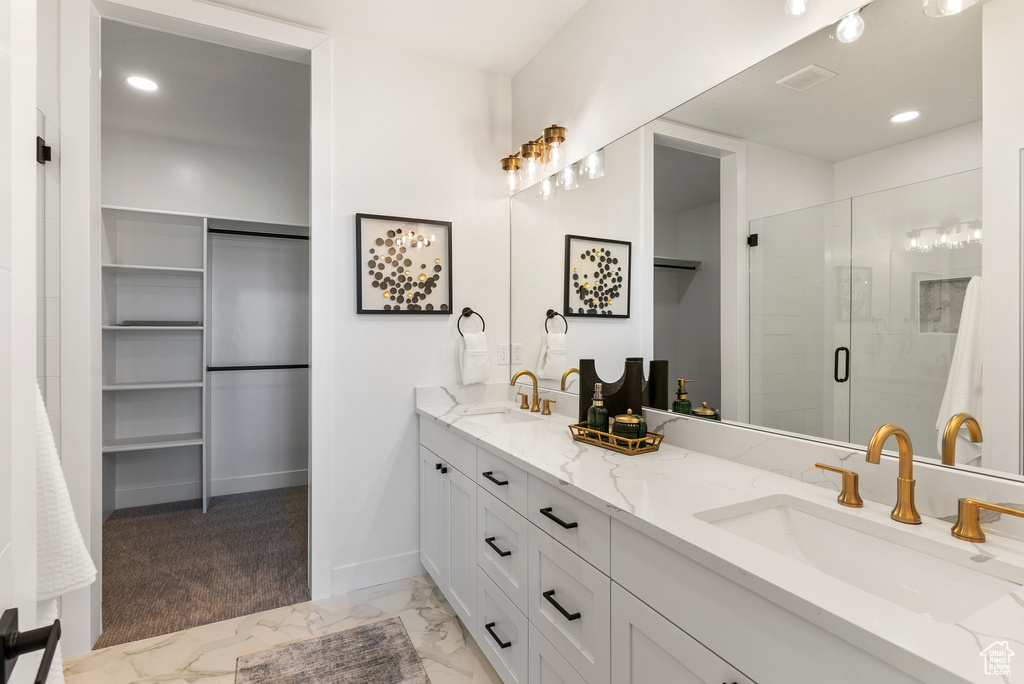 Full bath with a shower stall, a spacious closet, double vanity, marble look tile flooring, and recessed lighting