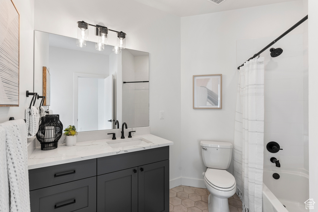 Full bathroom featuring toilet, vanity, tile patterned flooring, baseboards, and shower / bath combo with shower curtain