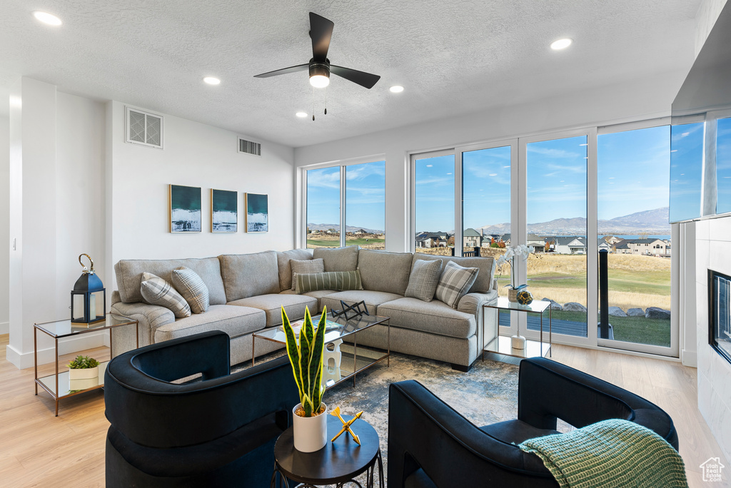 Living area featuring recessed lighting, light wood-style flooring, a textured ceiling, a ceiling fan, and a mountain view