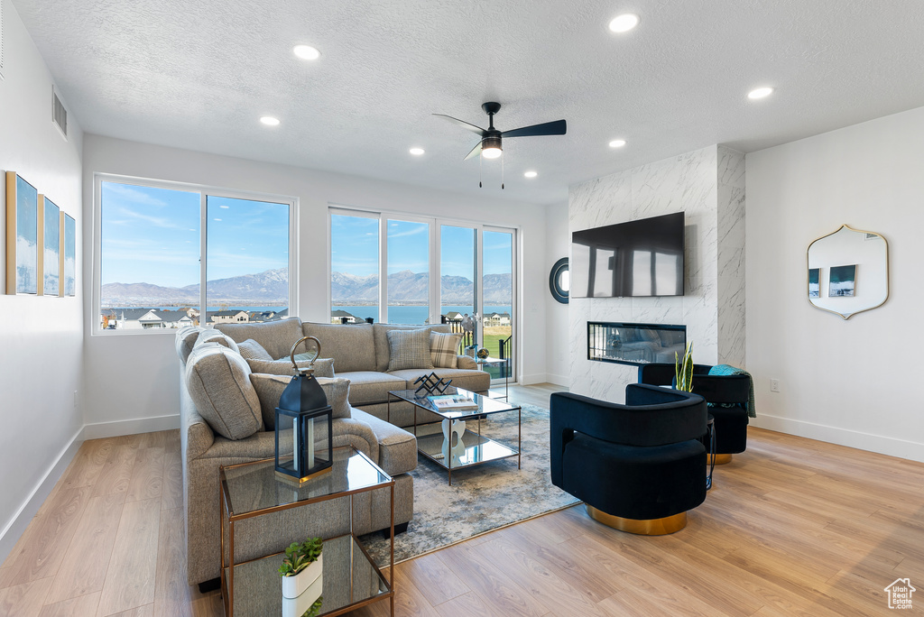 Living area featuring ceiling fan, baseboards, wood finished floors, a fireplace, and recessed lighting