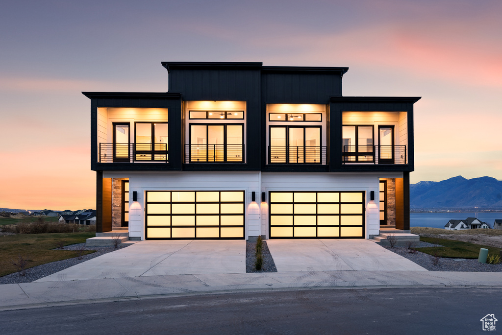 Contemporary house featuring a balcony, a garage, concrete driveway, and a mountain view