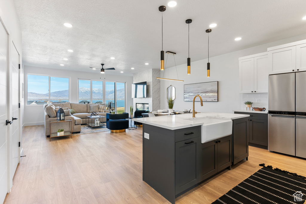 Kitchen with stainless steel refrigerator, a sink, light wood-style flooring, recessed lighting, and open floor plan