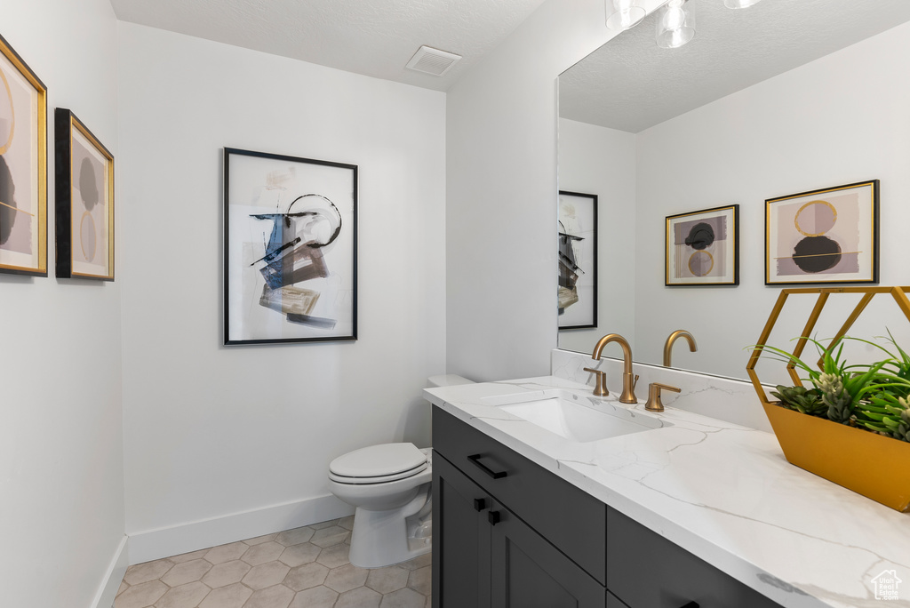 Bathroom featuring vanity, baseboards, toilet, and tile patterned floors