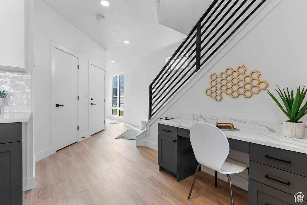 Office featuring built in study area, light wood finished floors, and recessed lighting