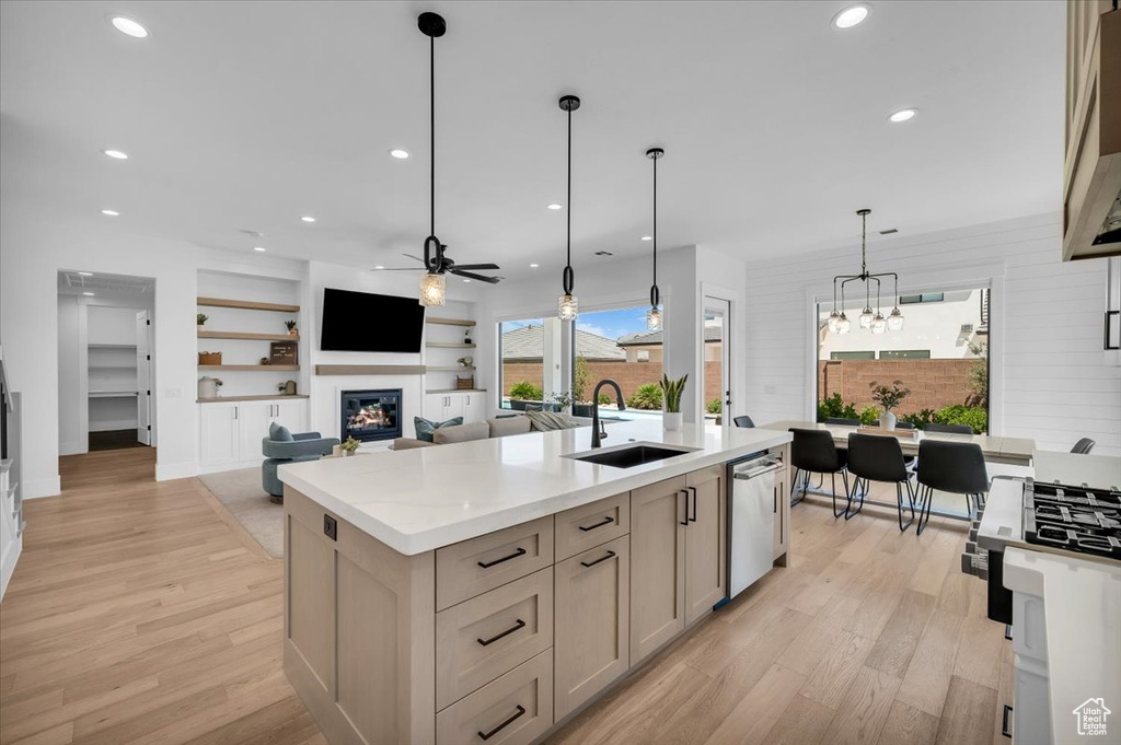 Kitchen with ceiling fan, stainless steel dishwasher, a glass covered fireplace, light wood-style floors, and recessed lighting