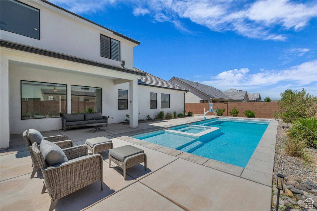 View of pool featuring a pool with connected hot tub, a patio area, an outdoor hangout area, and a fenced backyard