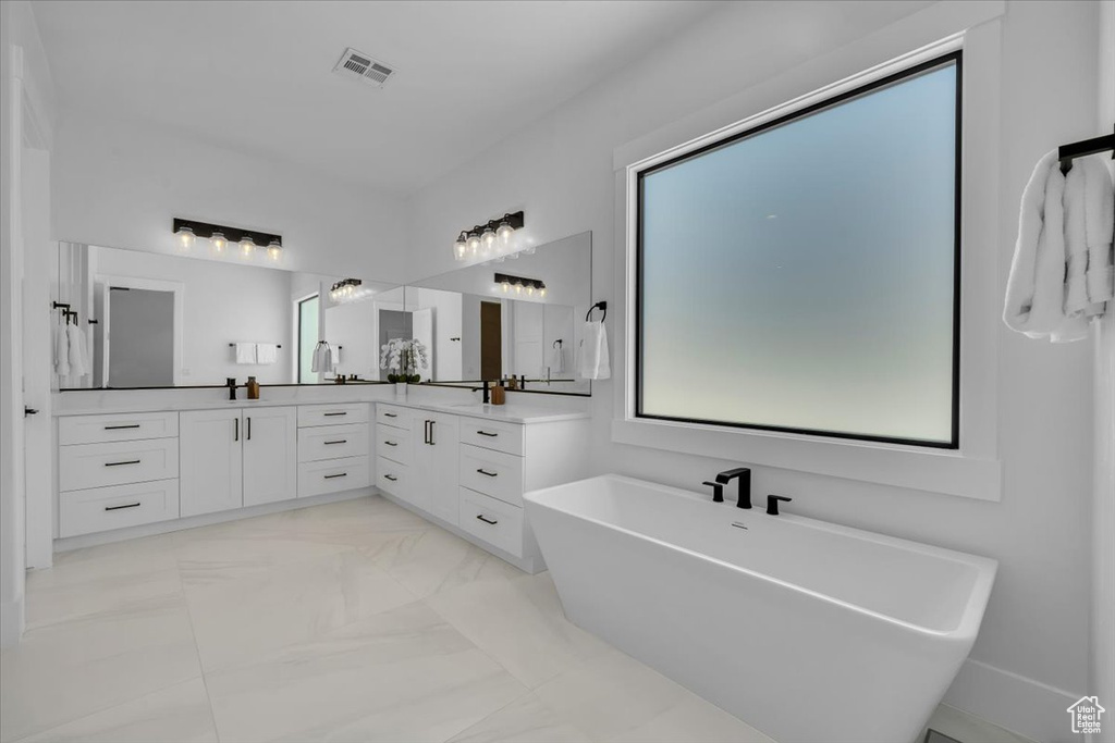 Bathroom with a freestanding tub, vanity, and marble finish flooring